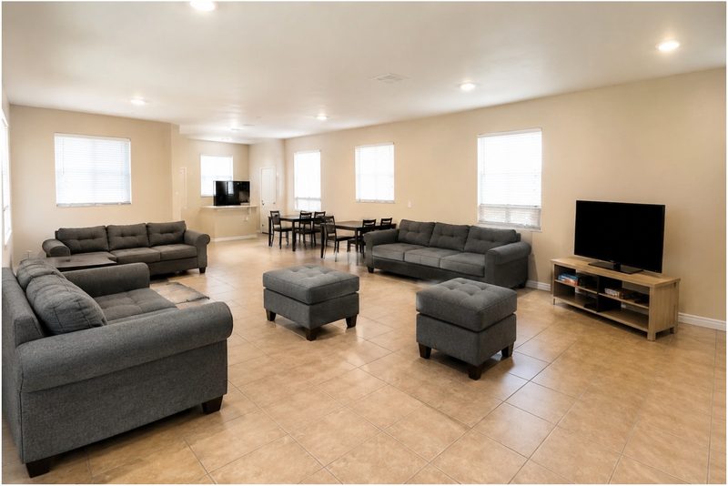 Living and dining area at 1448 with three sofas, ottomans, and a shared dining table